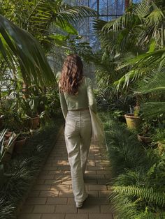 a woman walking down a path in a greenhouse