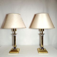 two lamps sitting on top of a white table next to each other with one light turned off