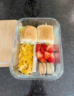 a plastic container filled with sandwiches and fruit