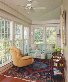 a living room filled with furniture and windows next to a rug on top of a hard wood floor