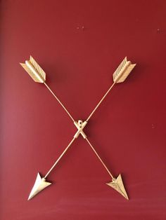 three gold arrows on a red wall with one arrow pointing in the opposite direction, and two smaller ones at the other end