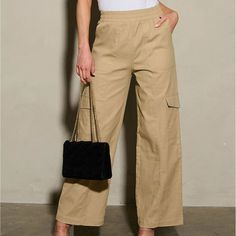 Expertly Constructed With 97% Cotton And 3% Spandex, These Wide Leg Pants Feature An Elastic Waist For A Comfortable Fit. With Cargo Pockets For Added Functionality, These Pants Are A Must-Have For Any Wardrobe. Model Is Wearing Size S With 40" Length, 13" Waist, And 29" Inseam. **New** Beige Cargo Pants With Elastic Waistband For Work, Spring Wide Leg Pull-on Cargo Pants, Stretch Khaki Straight Cargo Pants, Khaki Stretch Straight Cargo Pants, Stretch Beige Cargo Pants, Beige Stretch Cargo Pants, Casual Stretch Parachute Pants For Workwear, Beige Utility Pants With Elastic Waistband, Spring Cargo Pants With Pull-on Style And Straight Fit