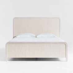 a white bed with two pillows on top of it