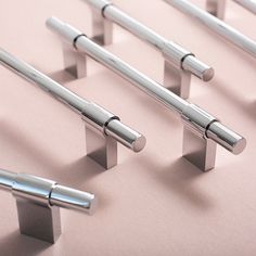 several metal handles on a pink surface with one closed and the other closed in different positions