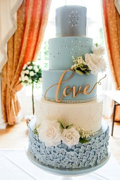 a blue and white wedding cake sitting on top of a table next to a window