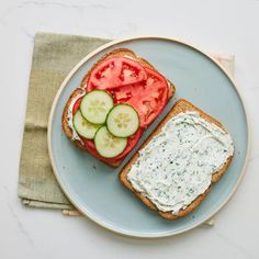 a sandwich with cucumber and tomato slices on it sitting on a blue plate