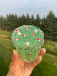 a person holding up a green drink in front of the camera with lots of bubbles on it