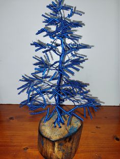 a small blue tree sitting on top of a wooden stump