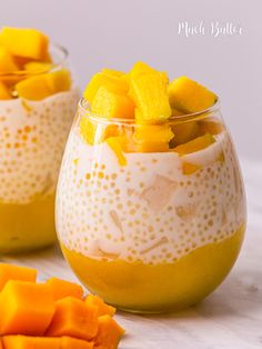 two glasses filled with fruit and yogurt sitting on top of a white table