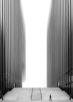 a person walking up some steps in front of tall buildings with columns on each side