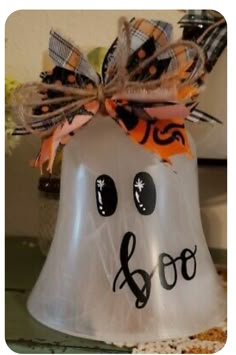 a white plastic bell shaped like a ghost with black eyes and a bow on it's head