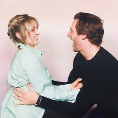 a man and woman are sitting on a chair together, one is holding the other's back