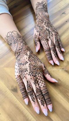 two hands with henna tattoos on them, one is showing the intricate pattern and the other