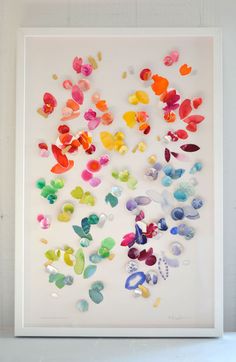 an art piece with many different colored butterflies on the wall in front of a window