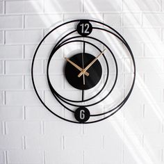 a black clock on a white brick wall with the numbers twelve and nine below it