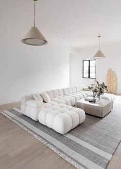 a large white sectional couch sitting on top of a rug in a living room next to a window