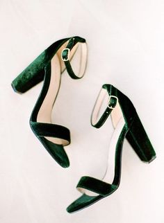 a pair of green high heeled shoes sitting on top of a white surface