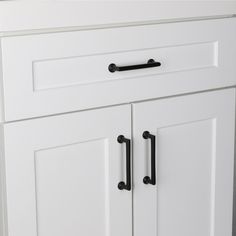 a white cabinet with two black handles on it