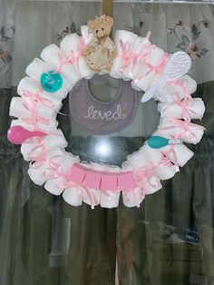 a teddy bear wreath with pink ribbon and white diaper around it that says loved