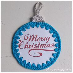 a blue and white christmas ornament hanging from a string on a wall with the words merry christmas written in red