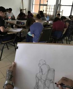 people sitting at desks and drawing on paper