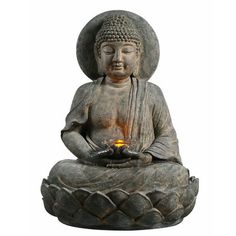 a buddha statue sitting on top of a lotus flower pot with a lit candle in it