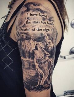 a woman's arm with a wolf and quote tattooed on the upper half of her arm