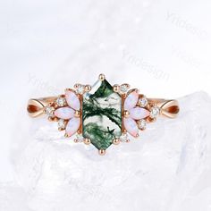 a green and white stone ring on top of a rock with diamonds in the middle