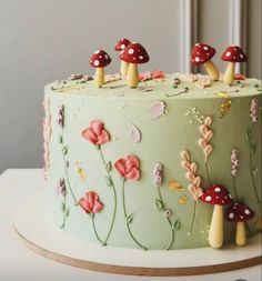 a green cake decorated with mushrooms and flowers