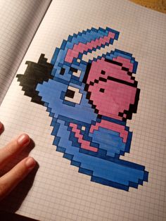 a hand is holding an open book with pixel art on it