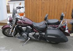 a maroon motorcycle parked next to a wooden fence