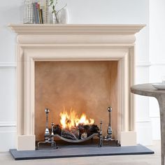 a fire place in the middle of a room with a table and chair next to it