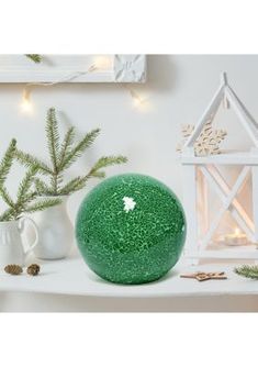 a green ball sitting on top of a white shelf next to a potted plant