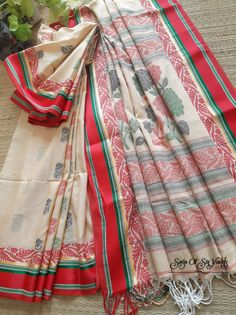 This saree is a pleasing and beautifully designed piece of clothing. The combination of the tussar mercerized cotton fabric with the traditional red weave border and the red satin finish border with green threadwork creates a unique and elegant look. The addition of the jamdani work adds further depth and detail to the saree, while the woven small floral motifs throughout the saree help to tie the design together. The wide panel design and floral motif on the pallu provide a focal point and make the saree stand out. The saree comes with a border-woven blouse piece, which should complement the saree perfectly. Overall it's a stunning and well-crafted piece of clothing that would be perfect for any special occasion. Details: Blouse: With Blouse Piece Saree length: 6.5 meters [BP Include] Sar Luxury Handloom Dupatta For Traditional Ceremonies, Luxury Woven Motif Dupatta For Puja, Luxury Handloom Fabric For Traditional Ceremonies, Festive Cotton Saree With Block Print, Cotton Dupatta With Woven Motifs For Diwali, Red Cotton Unstitched Saree, Cotton Saree With Woven Motifs, Multicolor Cotton Saree With Block Print, Multicolor Cotton Dupatta With Woven Motifs