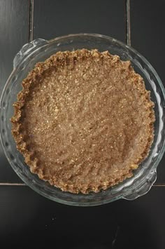 a pie crust in a glass dish on a black counter top with tile flooring