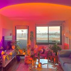 a living room filled with lots of furniture and colorful lights on the ceiling above it