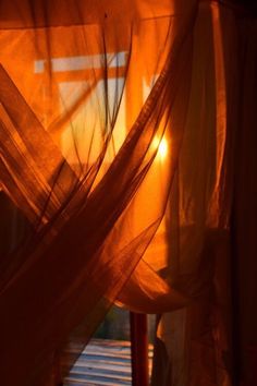 the sun is shining through some sheer curtains