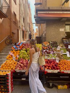 a woman standing in front of a fruit stand