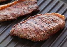 two steaks sitting on top of a grill