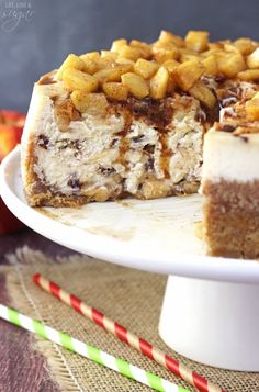 a cake on a plate with one slice cut out and apples in the back ground