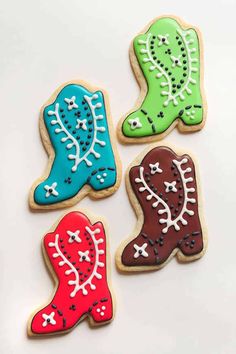 three decorated cookies are shown on a white surface with one cookie in the shape of a cowboy boot