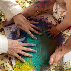 three people with their hands on the ground covered in colored paint and kneads