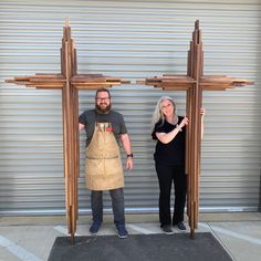 two people standing in front of a wooden cross