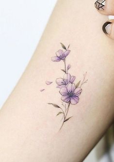 a woman's arm with purple flowers and leaves on the left side of her body