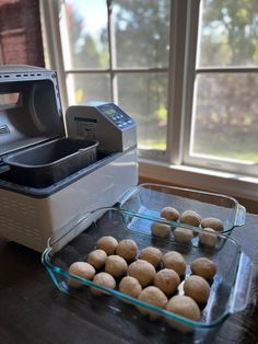 some food is sitting on a table next to a machine and tray with doughnuts