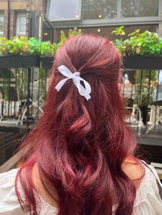 a woman with long red hair wearing a white bow