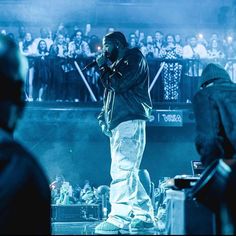 a man standing on top of a stage with a microphone in front of an audience