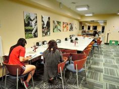 two women sitting at a table in a room with chairs and pictures on the wall