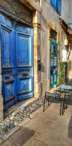 an alleyway with tables and chairs in front of blue doors