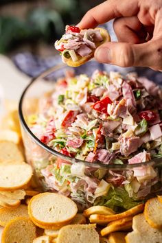 a person is dipping some food into a bowl with chips on the table next to it